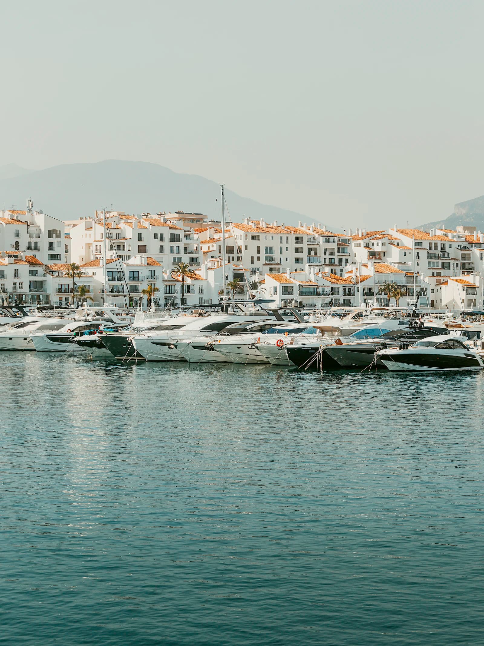 Motor yachts moored along a Mediterranean harbour town